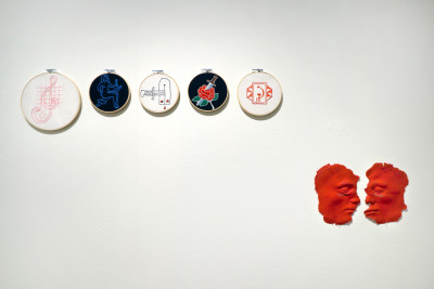 Fünf runde Stickereien mit Symbolen aus der Gefängniskultur Sibiriens. Rote Abformungen zweier Gesichter, die flach an die Wand genagelt wurden of Siberia. Red molding of two faces nailed flat to the wall.