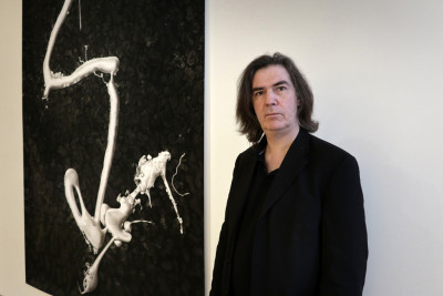 Der Künstler Peter Hock steht rechts neben seinem großformatigen Bild an der Wand links neben ihm.