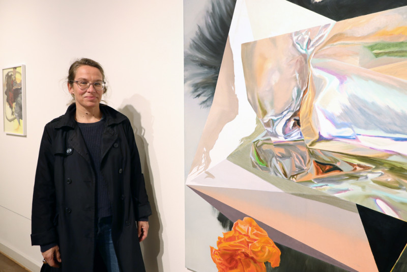 Die Künstlerin Maja Rohwetter steht links von ihrem Gemälde in der Galerie.