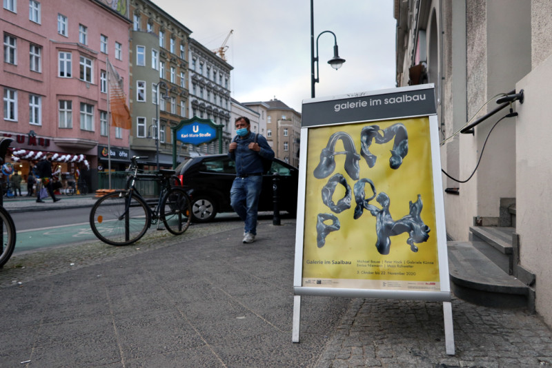 Das Schild mit dem Plakat zur Ausstellung mit dem Schriftzug AMORPH steht auf der Karl-Marx-Straße vor dem Eingang zur Galerie im Saalbau
