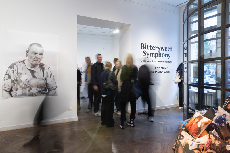 text: >
  Ausstellungsansicht der Ausstellung
  Bittersweet Symphony mit Besuchern vor
  einer Porträtfotografie und einem
  Wandtext mit Ausstellungstitel
decorative: false
source: reviewed