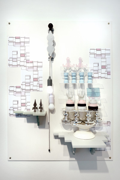 Art installation on the wall. Materials: Light bulbs, paper stuck on the wall, shapes, metal parts and glass stacked up like a cake.