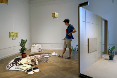 View of the room. View behind the mediterranean room installation. A person looks at the artwork.