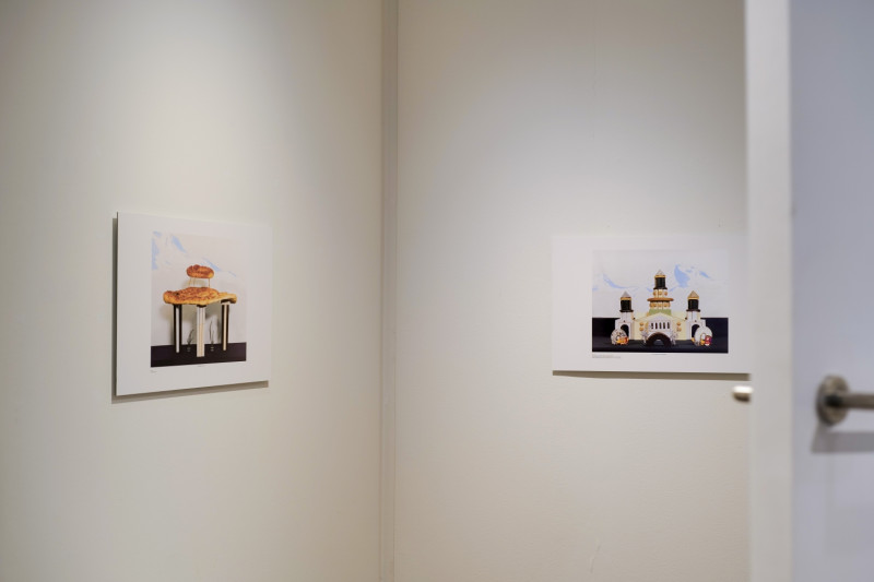 An der Wand hängen zwei Bilder, auf denen Architektur-Bauten in Kombination mit Lebensmitteln gezeigt sind.