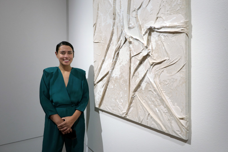 die Künstlerin steht neben ihrer Leinwand