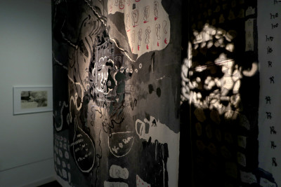 ein bemalter und geschnittener Stoff hängt im Raum