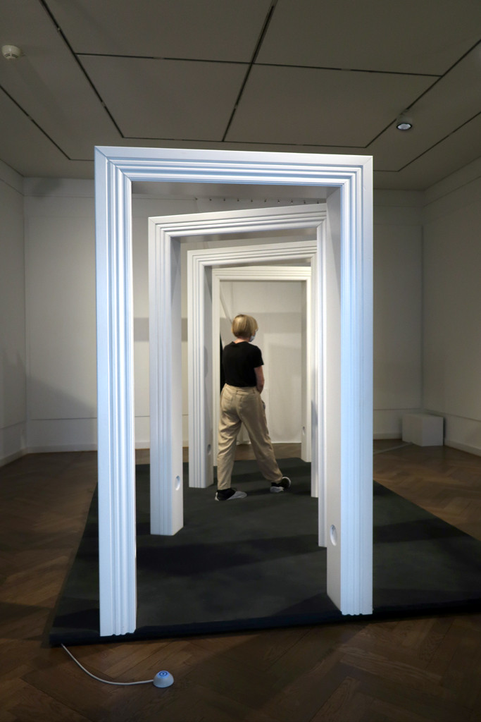 eine Besucherin durchschreitet die großen weißen Türrahmen