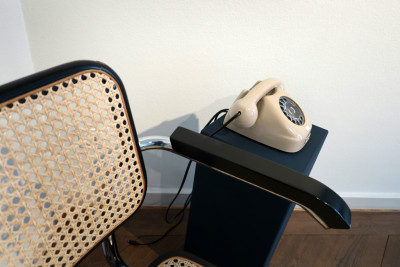 ein beiges Drehscheibentelefon steht auf einem blauen Sockel