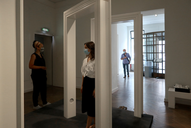 Besucher durchschreiten die großen weißen Türrahmen in der Ausstellung