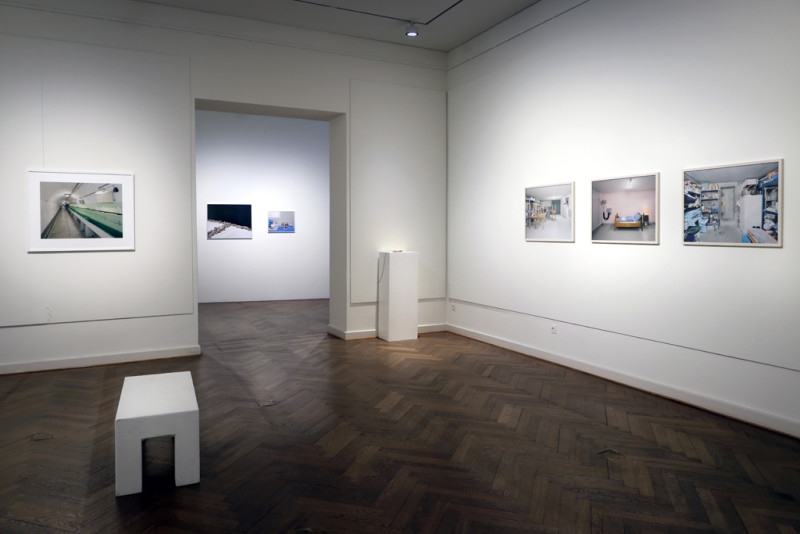 Vier 4x5 Inch Fotografien in großen querformatigen weißen Bilderrahmen zeigen Innenräume von Bunkeranlagen in der Schweiz