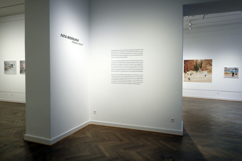 Auf einer weißen Wand sieht man den Schriftzug mit dem Titel der Ausstellung: 