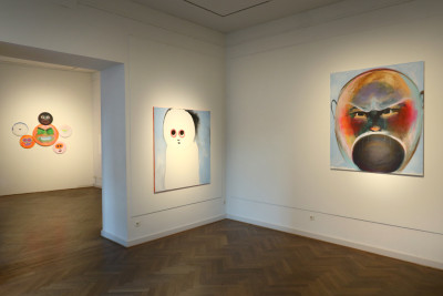 View through the premises. Two large emotional pictures hang in the foreground . Round pictures hang on the wall in the background.