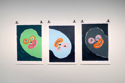 Three colourful pictures with cheeky faces hang on the wall.