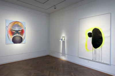 Two large pictures and a small sculpture looking at itself in the mirror hang on the wall.