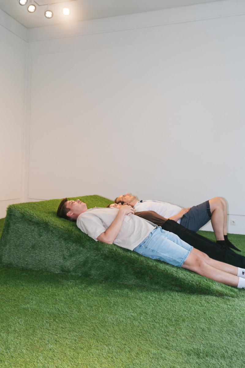 text: >
  Zwei Personen liegen entspannt auf einer
  grünen Kunstrasen-Installation in einem
  weißen Galerieraum
decorative: false
source: reviewed