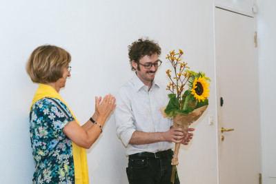 Künstler*in Vinzenz Aubry bekommt zur Eröffnung Blumen überreicht