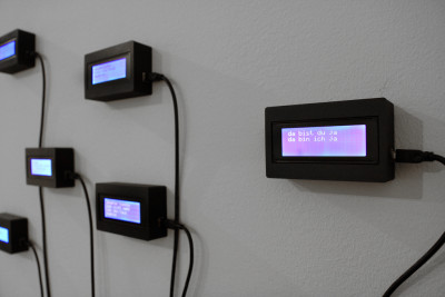 Kleinformatige Displays hängen an der Wand, auf denen fragmentarisch Sätze aufleuchten