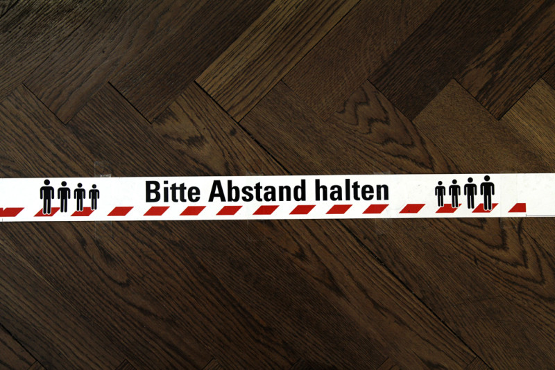 Markierungsband auf dem Boden mit dem Hinweis „Bitte Abstand halten