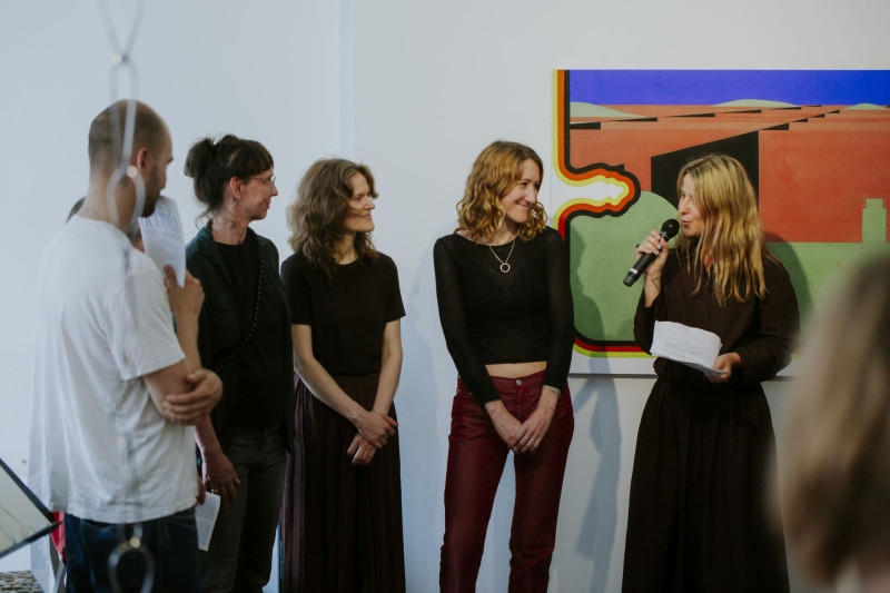 Group photo at the opening of the exhibition nebula at Galerie im Saalbau: from left to right Louis Hay, Ani Schulze, Nina Laaf, Jana Schulz, Isabella Fürnkäs, and curator Diana Nowak (right) standing side by side in front of the audience.