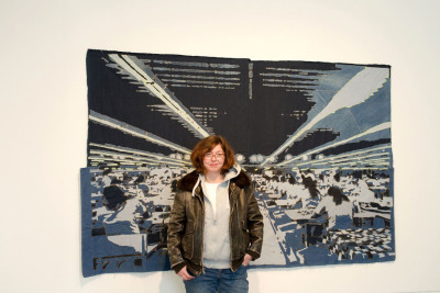 Die Künstlerin Katrin Hoffert steht vor ihrem genähten Jeansbild.