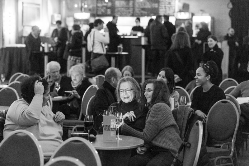 Menschen sitzen im Saal vom Heimathafen Neukölln.