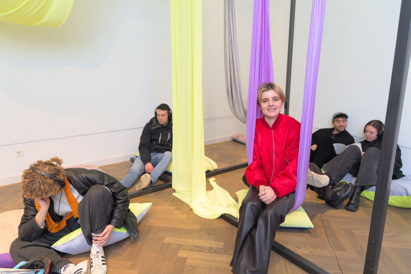 The picture shows the artist in a lilac-colored hammock in her work 