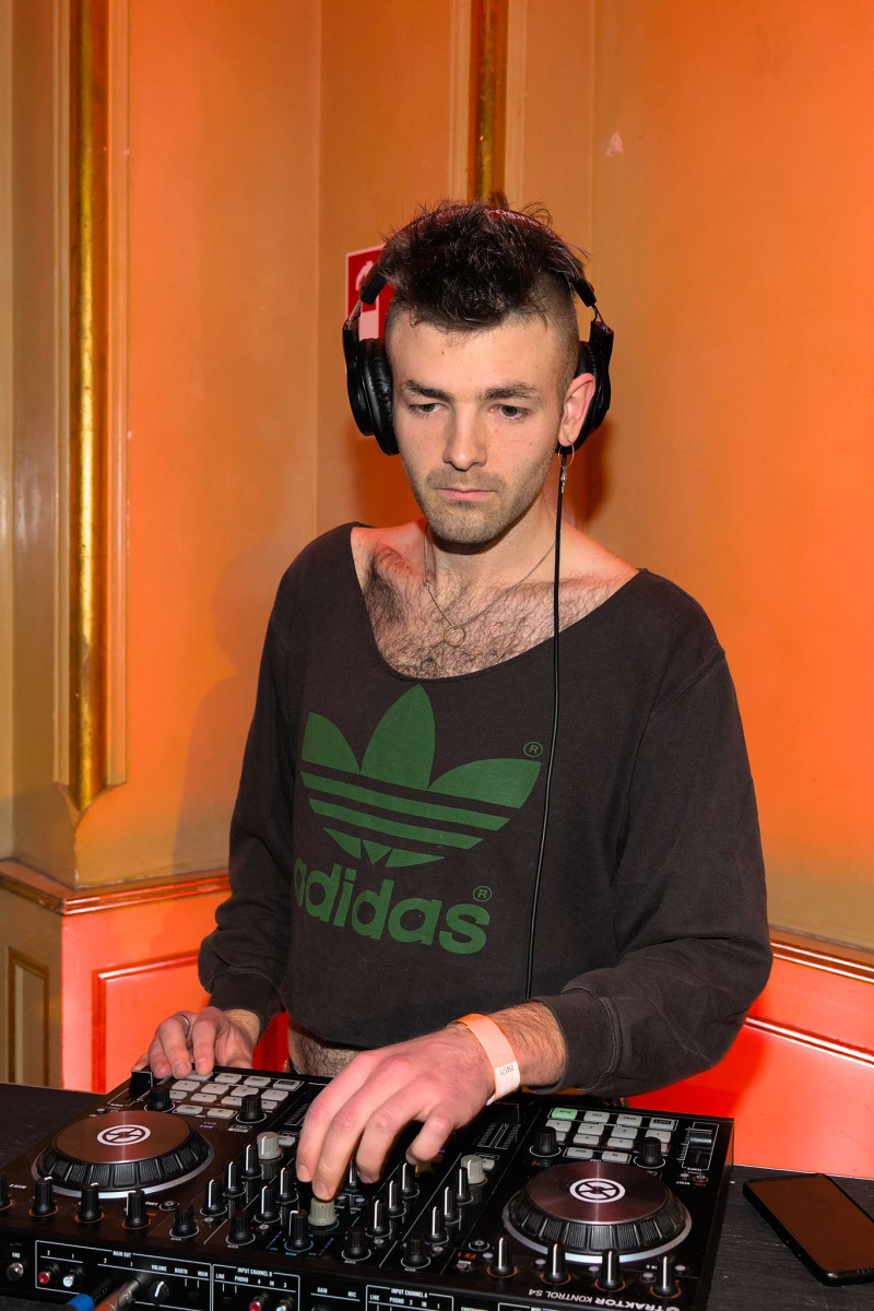 Der DJ vor seinen Turntables vor einer orangefarbenen Wand