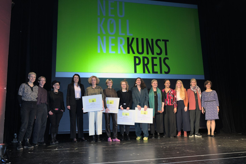 Die Preisträger:innen stehen gemeinsam mit der Jury und der Kulturstadträtin auf der Bühne des Heimathafen Neukölln
