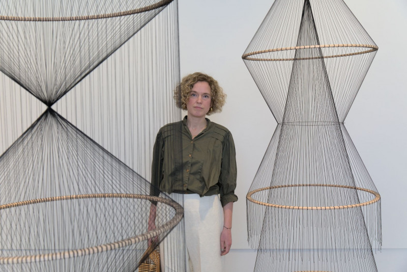 The artist Constanze Vogt stands behind her hanging installation 