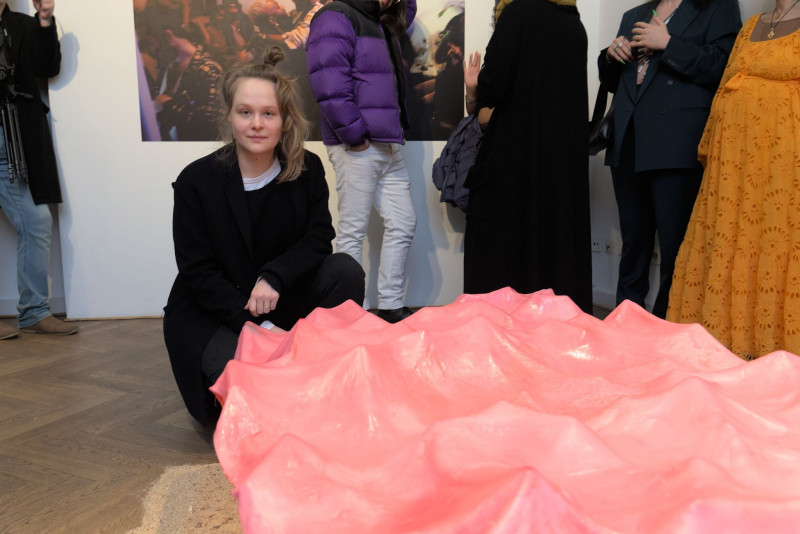 The artist sits in front of her installation made of pink cellulose