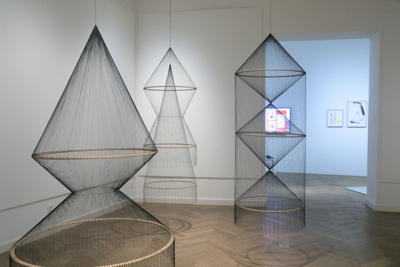 Das Bild zeigt hängende filigrane Objekte aus Holzreifen und schwarzen Baumwollfäden