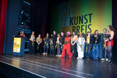Gallery staff, the nominated artists, and the members of the jury stand on a stage.