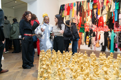 People at the exhibition opening. On display in the foreground is part of the work by musa michelle mattiuzzi and in the background the work by Va-Bene Elikem Fiatsi.