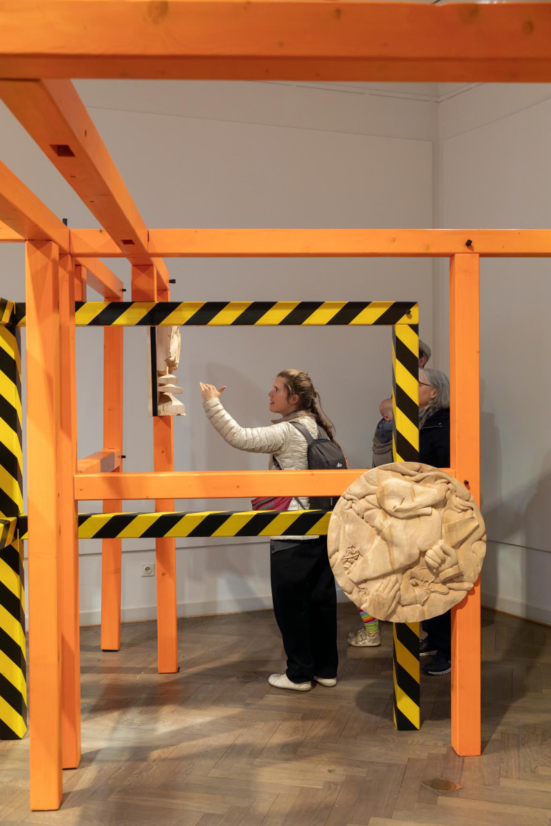 text: >
  Besucher interagieren mit einer
  orangefarbenen Konstruktion aus Balken
  in einem Galerieraum
decorative: false
source: reviewed