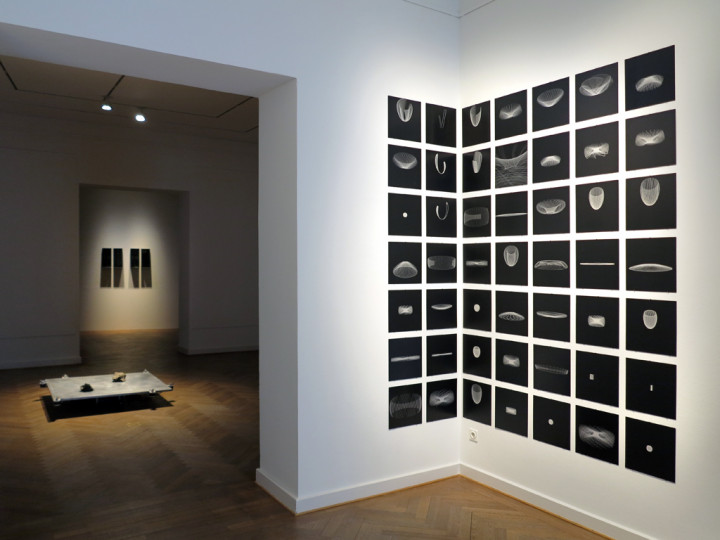 Eingangsbereich der Galerie mit schwarzen quadratischen Tafeln, in die Umlaufbahnen von Planeten graviert sind