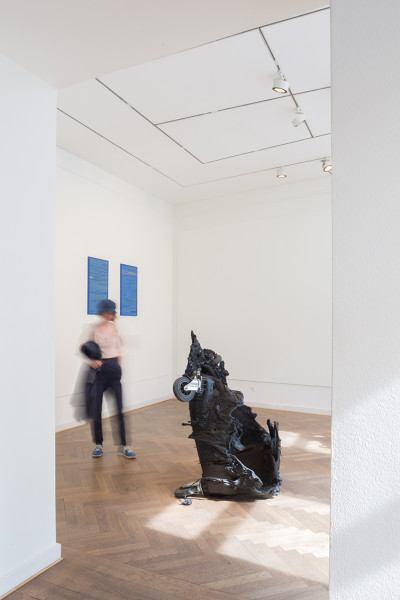 A visitor walks around a burnt trashbin