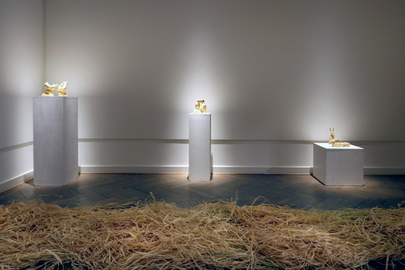 Raffia im Vordergrund und drei Skulpturen aus Lehm auf drei Sockeln platziert