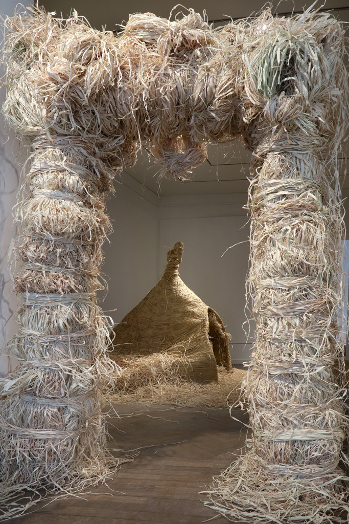 Installation view of the raffia portal and the clay sauna.
