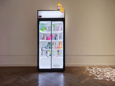 View of a refrigerator containing frozen neon-colored objects made of fabric and artificial hair.