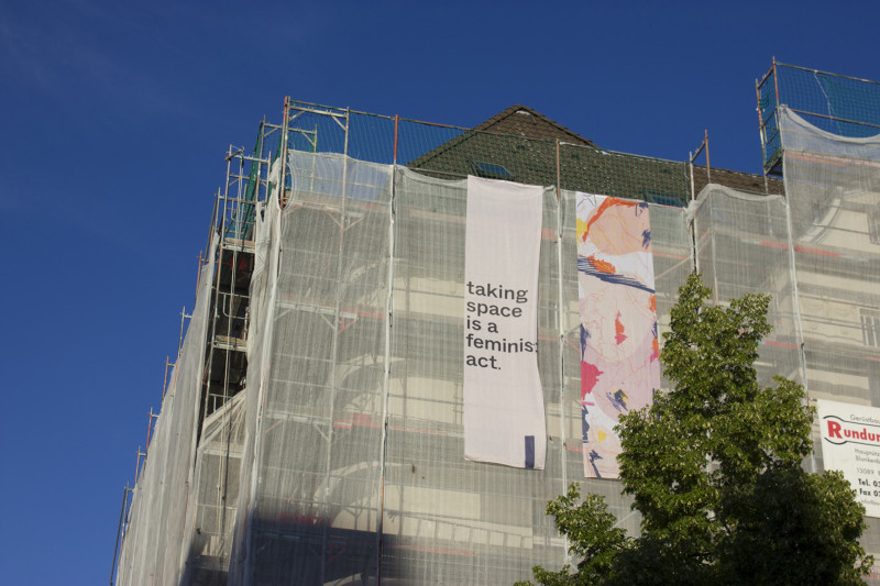 Auf einem Baugerüst hängt ein Banner mit dem Schriftzug 