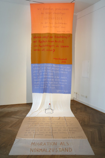 Ein langer Stoffbanner mit Vorderungen hängt von der Decke