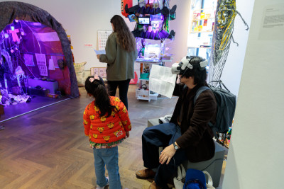A gallery space with a father and his young daughter. Artworks can be seen in the background.