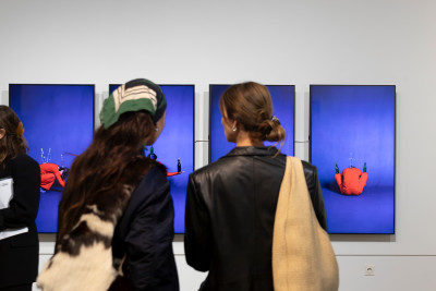 Two women are looking at four screens showing a video installation