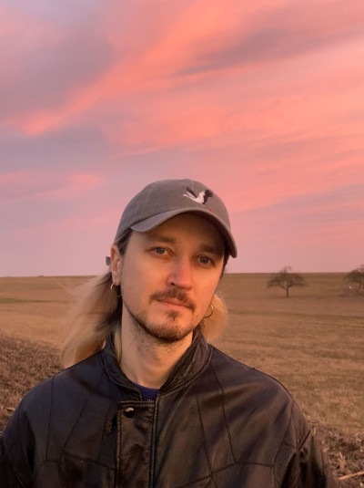 Der Künstler vor einer Landschaft mit rosanem Abendhimmel